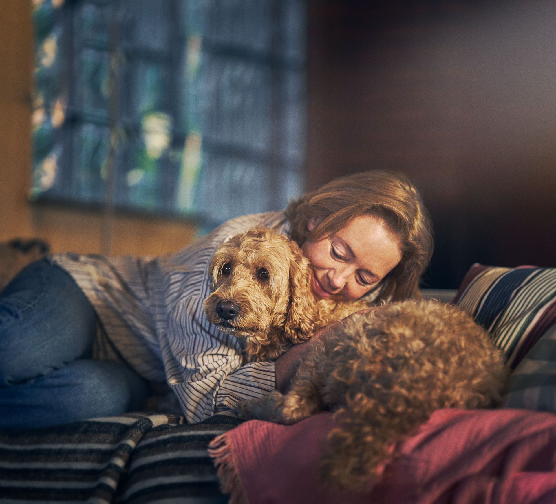 Frau liegt mit Hund auf der Couch.