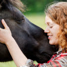 Frau kuschelt mit einem Pferd, das sie zur Verfügung hat